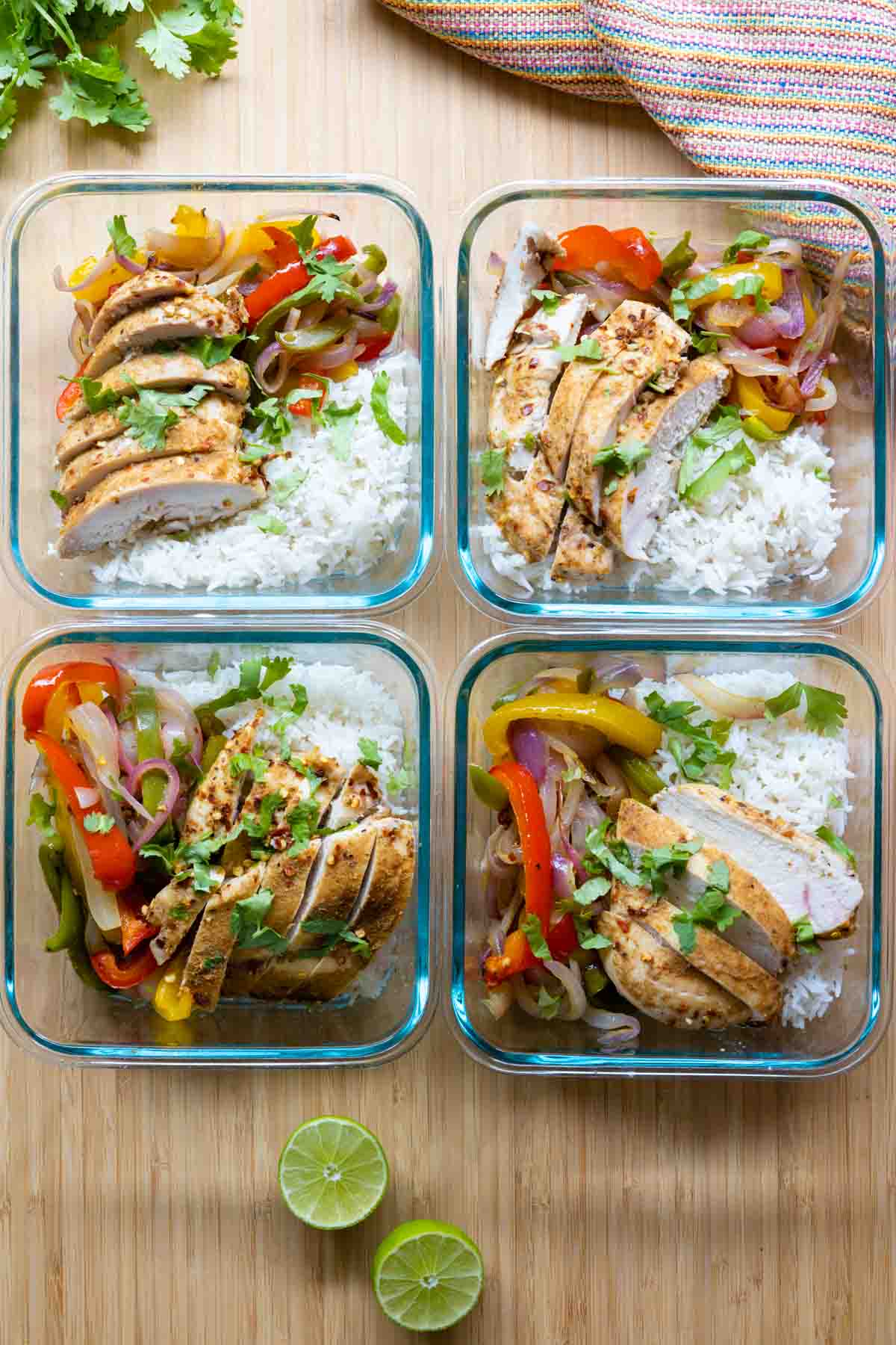 Four meal prep bowls filled with chicken fajitas and rice.