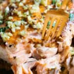 Closeup showing texture of cooked pan-seared salmon with garlic on top.