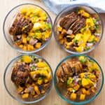 Four meal prep bowls filled with pork, mango, and sweet potatoes.