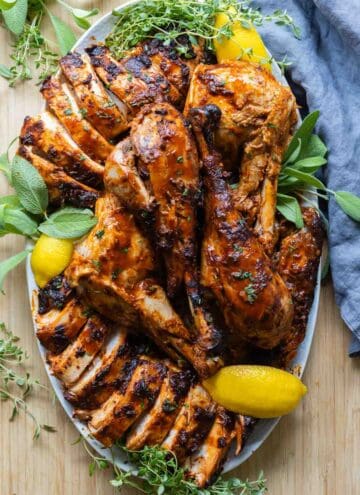 Carved and plated sooked whole turkey with deep dark Peruvian marinade and lemon slices and herbs as decoration.