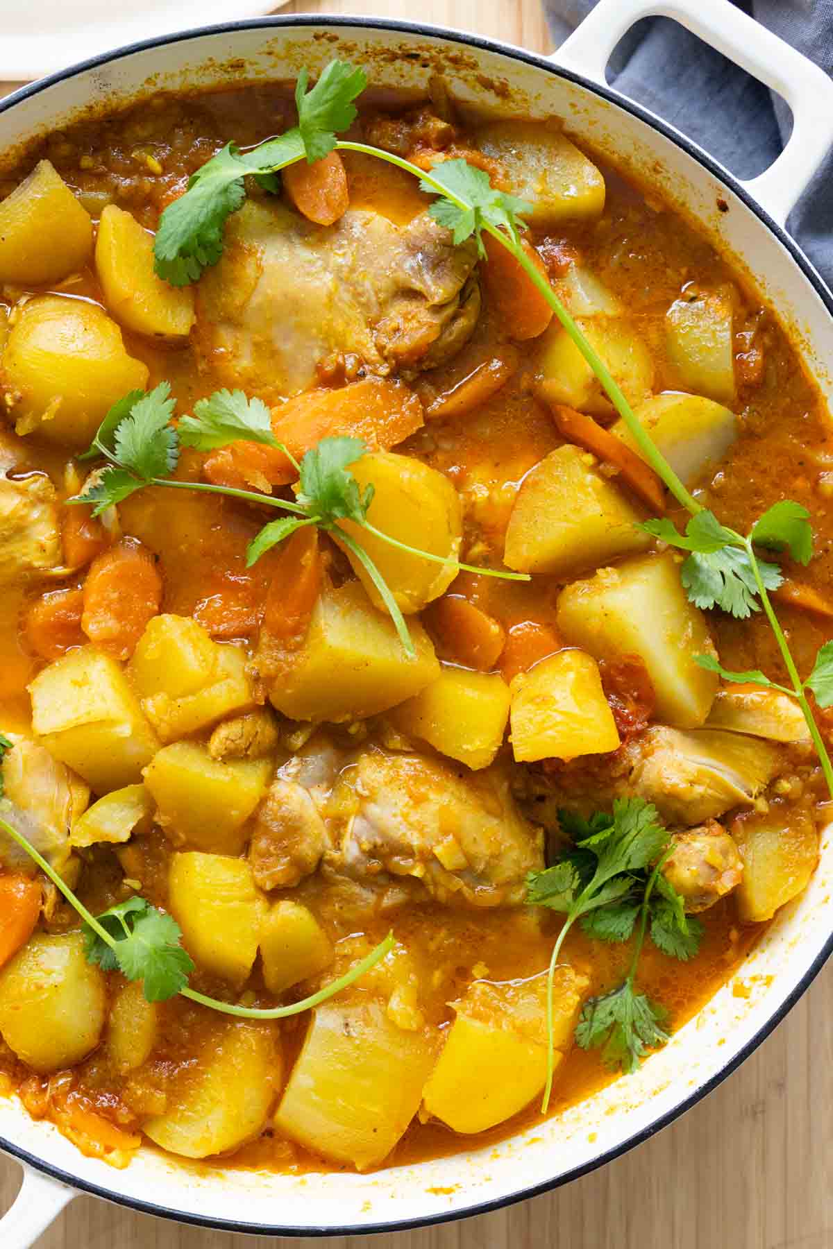 Mauritian Chicken Curry in a white cast iron pot garnished with cilantro.