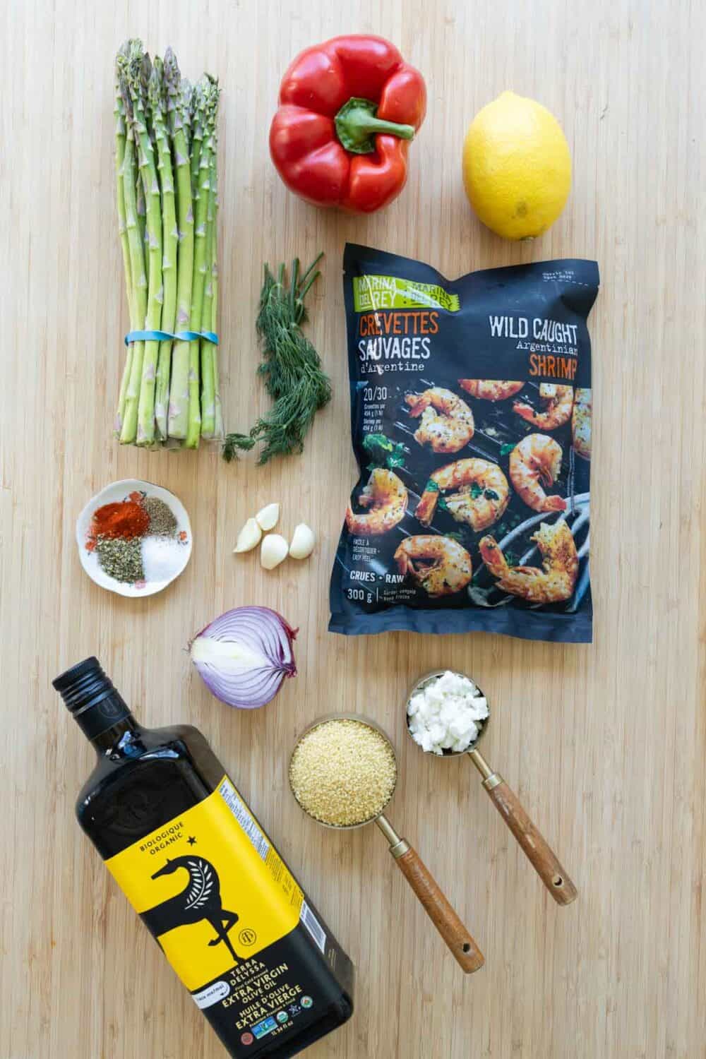 Ingredients for Sheet-Pan Shrimp With Veggies and Couscous laid out on a kitchen counter.